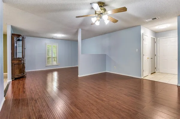 a view of an empty room with window and wooden floor