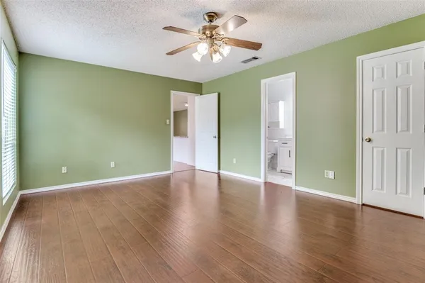 an empty room with wooden floor and a ceiling fan