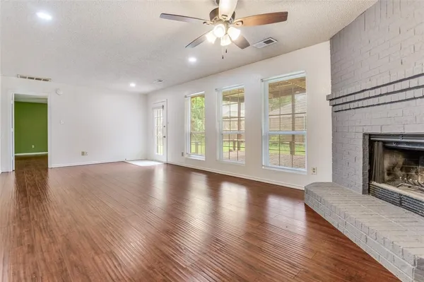 an empty room with windows fireplace and wooden floor