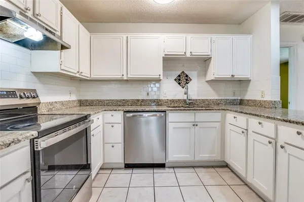 a kitchen with granite countertop a sink stove and cabinets