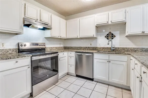 a kitchen with granite countertop white cabinets white stainless steel appliances and sink