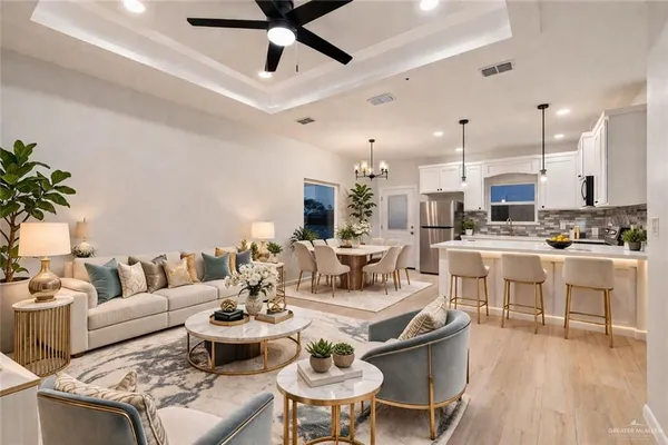 a living room with lots of white furniture and kitchen view