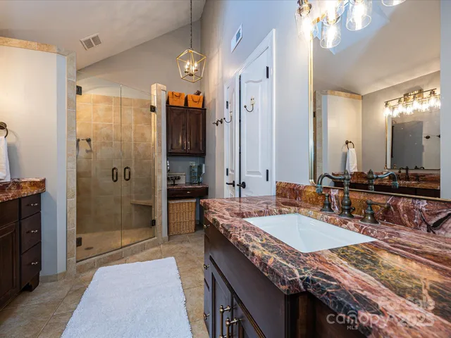 a bathroom with a granite countertop sink a toilet a mirror and shower