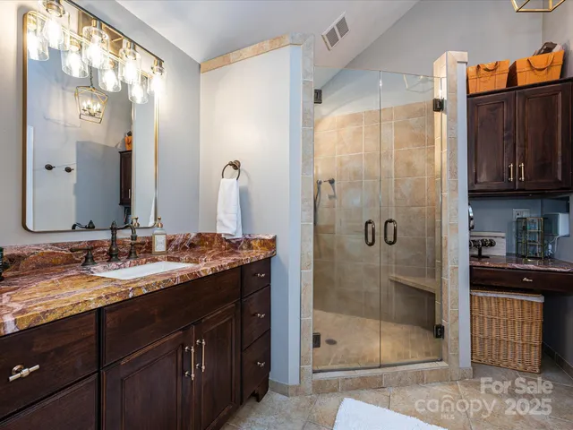a bathroom with a granite countertop sink a mirror and shower