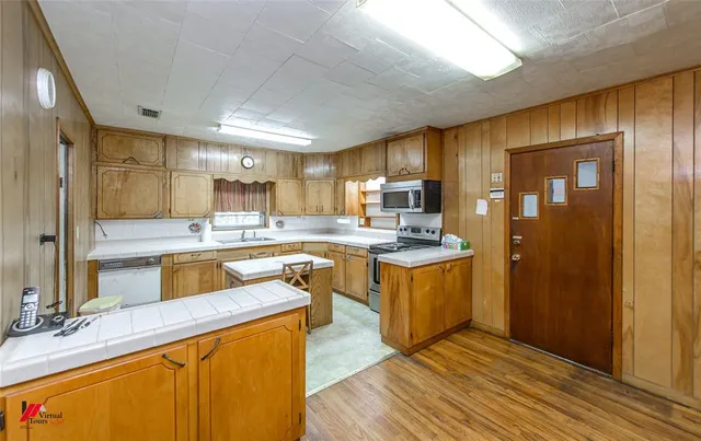 a kitchen with kitchen island granite countertop wooden cabinets and white appliances
