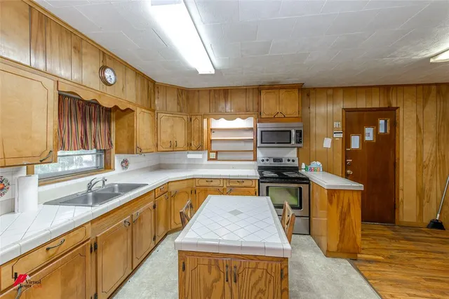 a kitchen with stainless steel appliances granite countertop wooden cabinets a stove and a sink