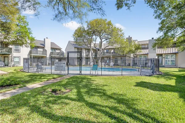 a view of a swimming pool with a bench and trees in the background