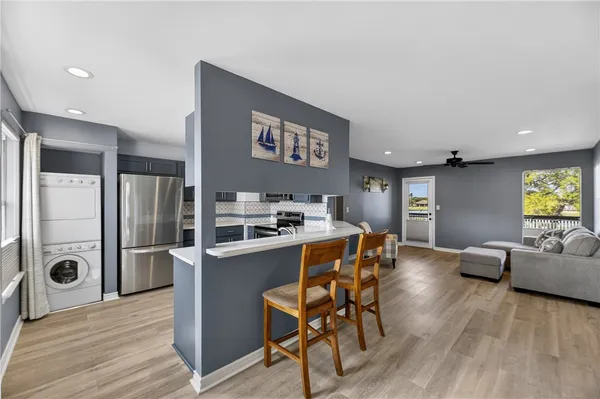 a kitchen with stainless steel appliances granite countertop a refrigerator a stove and a dining table with wooden floor