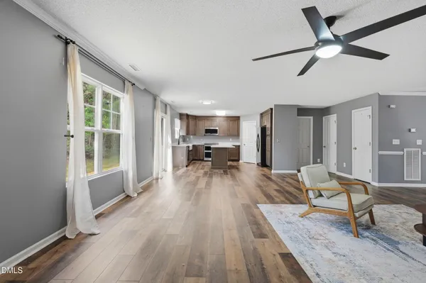 a view of empty room with wooden floor and fan