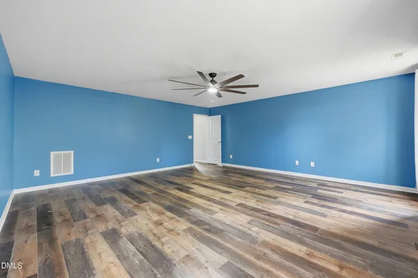 a view of an empty room with window and wooden floor