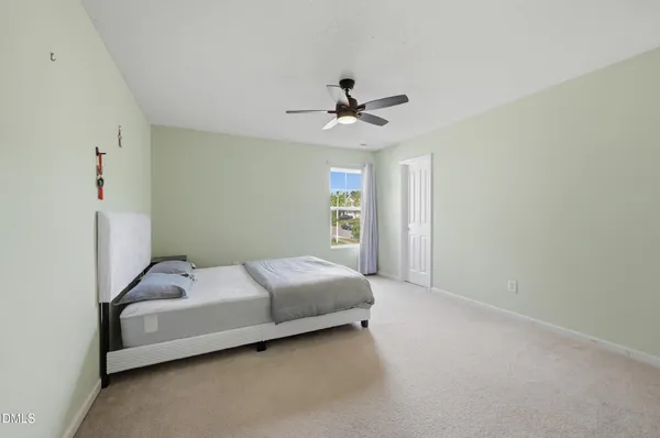 a view of an empty room with wooden floor and fan