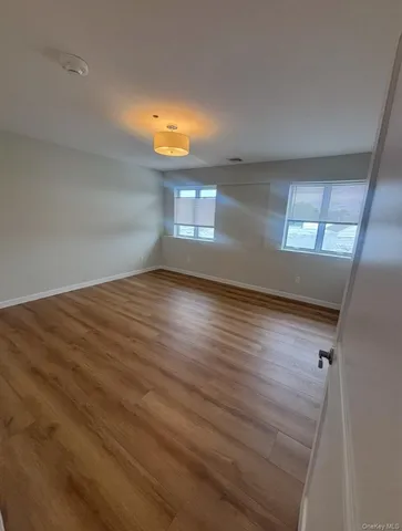 a view of empty room with wooden floor and window