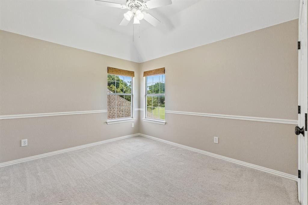 2925 Sunset Ridge McKinney, TX 75072 - Photo 19 of 33 Spacious upstairs bedroom offering soft neutral tones, vaulted ceilings, plush carpeting, and large windows that provide peaceful neighborhood views and exceptional natural light.