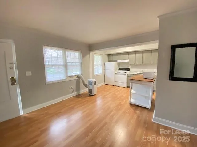 a view of a kitchen with kitchen island wooden floors and stainless steel appliances