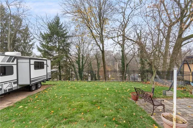 a view of a white house in front of a big yard with large trees