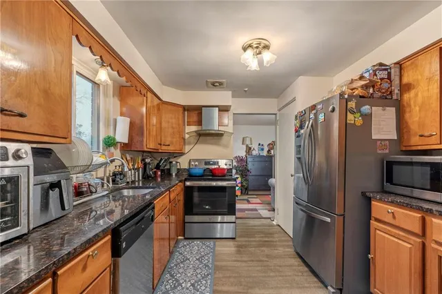 a kitchen with stainless steel appliances granite countertop a refrigerator a stove and a sink