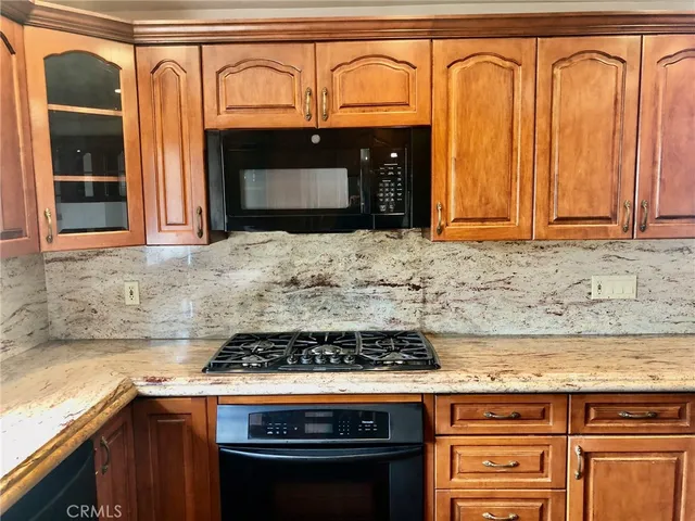 a kitchen with granite countertop a stove top oven microwave and cabinets