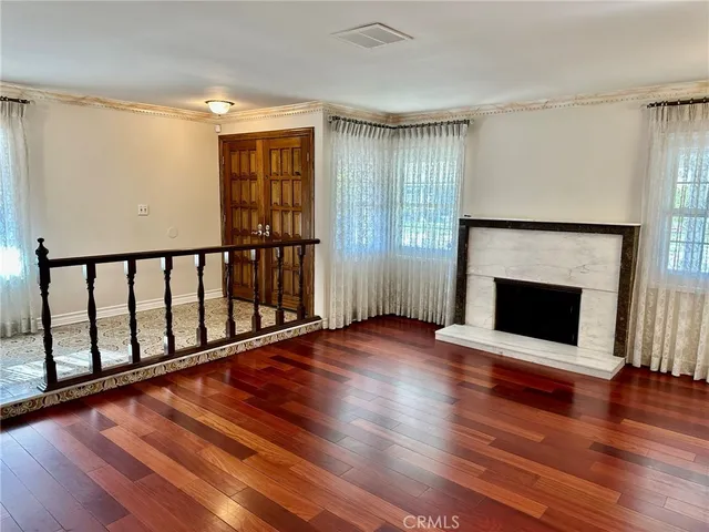 a view of an empty room with wooden floor fireplace and a window