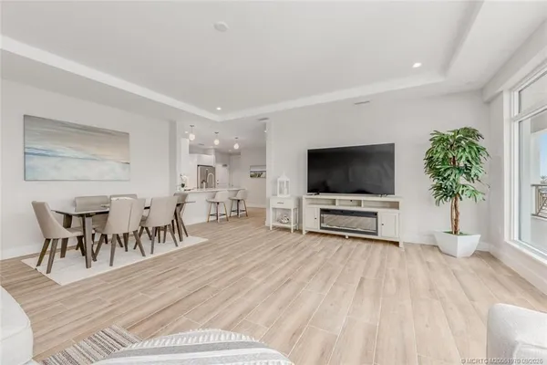 a kitchen with stainless steel appliances a refrigerator a stove a sink dishwasher and a dining table with wooden floor