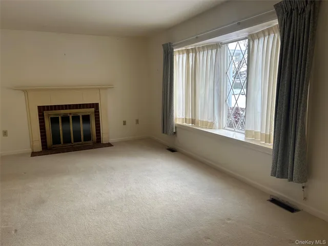 a view of an empty room with a window and fire place