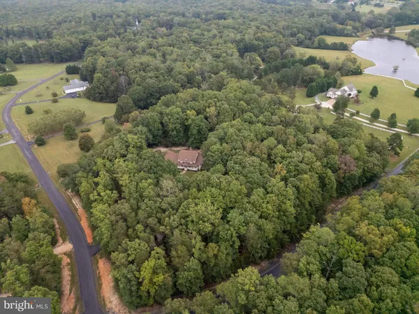 an aerial view of residential house with outdoor space and trees all around