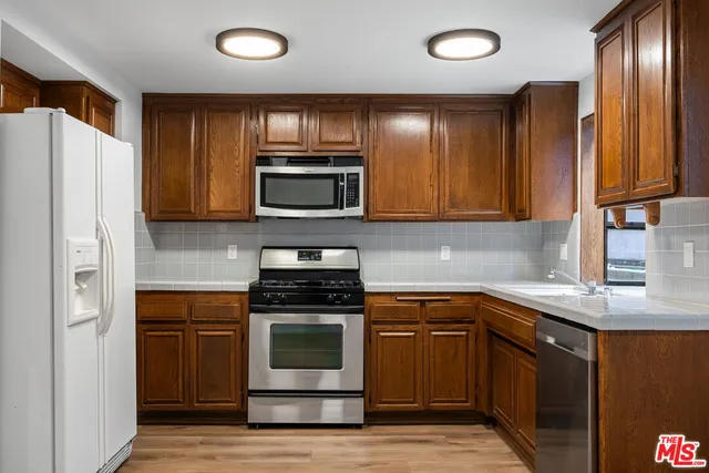 a kitchen with granite countertop wooden cabinets stainless steel appliances and a window