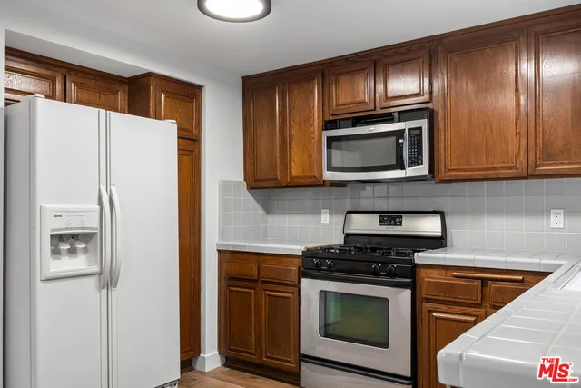 a kitchen with granite countertop cabinets stainless steel appliances and a wooden floor