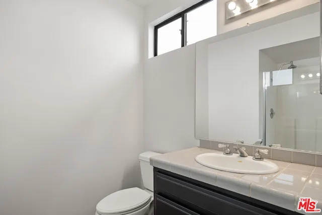a bathroom with a granite countertop toilet sink and mirror