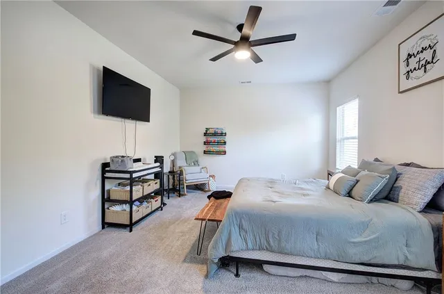 a bedroom with a bed a flat screen tv and a ceiling fan