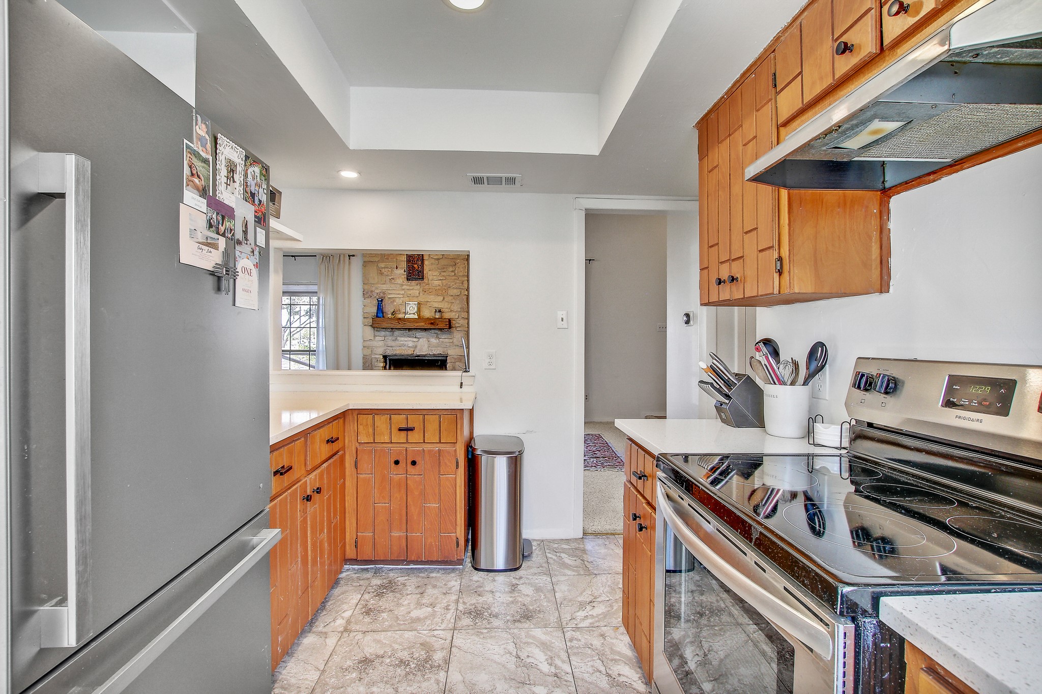 8925 North Plaza, Unit 69 Austin, TX 78753 - Photo 13 of 29 Kitchen with stainless steel appliances, brown cabinetry, under cabinet range hood, a tray ceiling, and recessed lighting