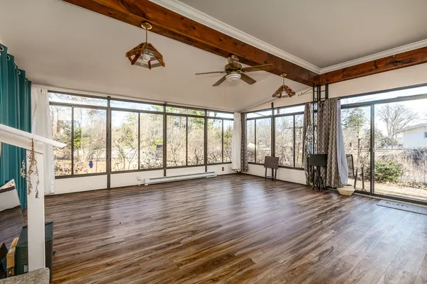 a view of an empty room with wooden floor and a window