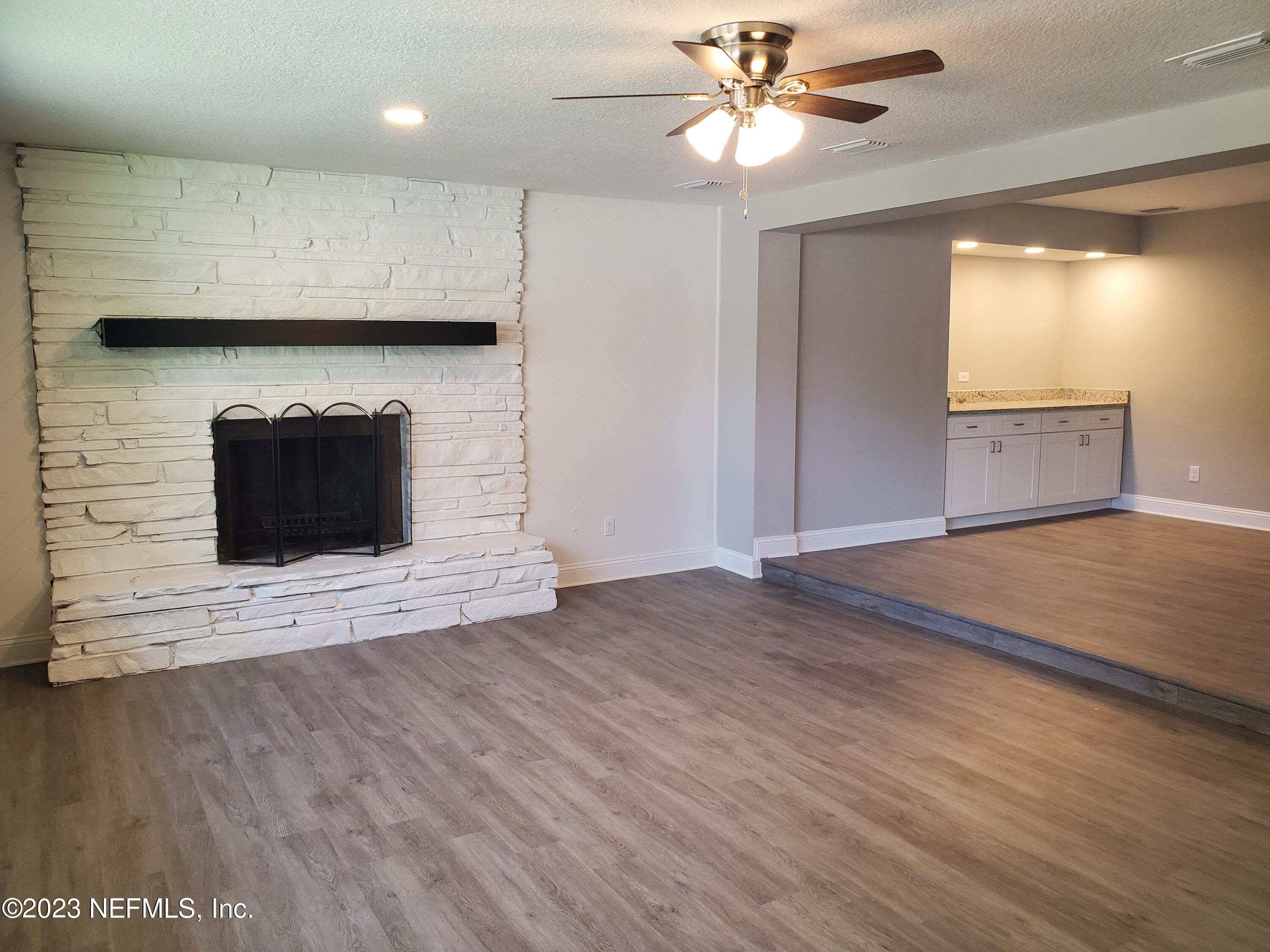 2305 Brest Road Jacksonville, FL 32216 - Photo 9 of 32 an empty room with wooden floor a ceiling fan a fireplace and windows