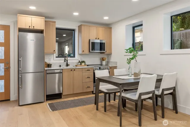 a kitchen with stainless steel appliances a refrigerator a stove a dining table and chairs