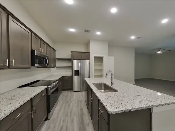 a kitchen with stainless steel appliances granite countertop a sink a stove and a refrigerator