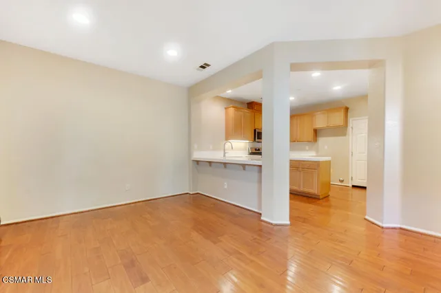 a view of empty room with wooden floor and a bathroom