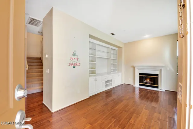 an empty room with wooden floor fireplace and windows