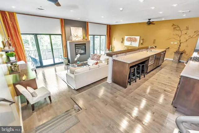 a living room with couches and kitchen view with wooden floor
