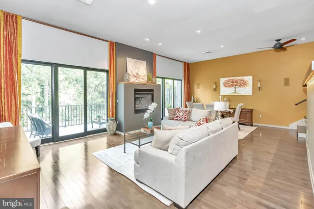 a living room with furniture large windows and wooden floor