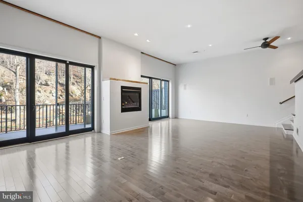a view of an empty room with a window and wooden floor