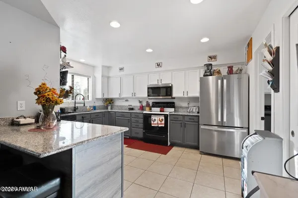 a kitchen with kitchen island granite countertop a sink dishwasher stove and cabinets with wooden floor