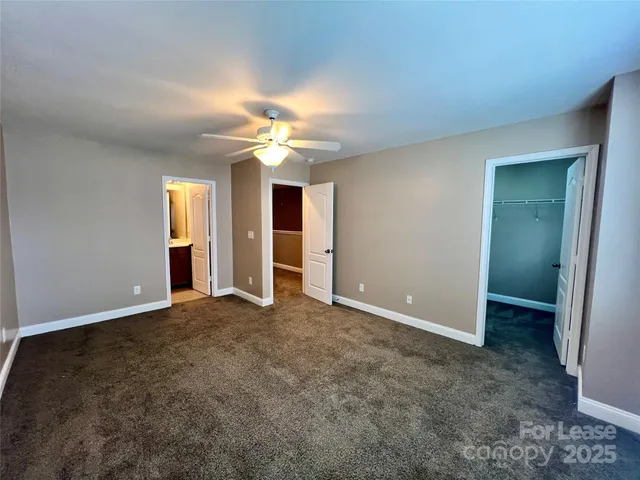 an empty room with chandelier fan and windows