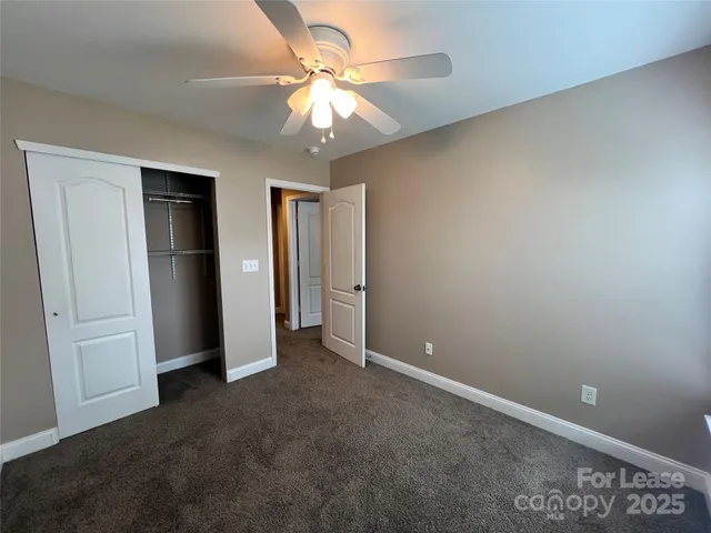 an empty room with closet and a ceiling fan