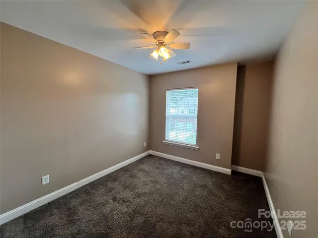 an empty room with a chandelier fan and windows