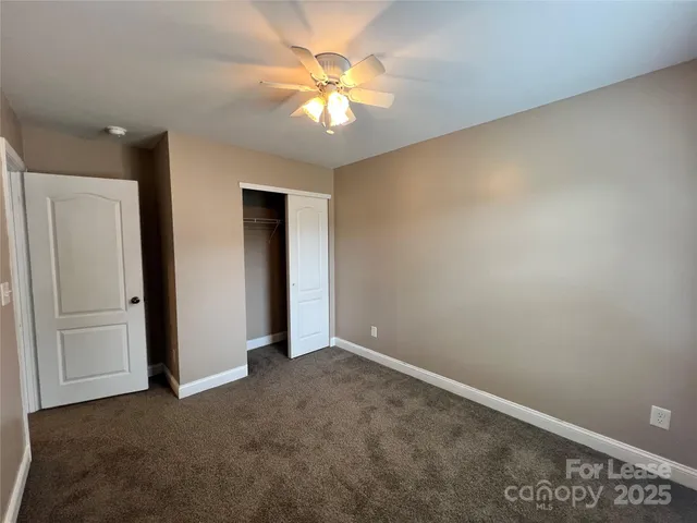 an empty room with closet and a chandelier fan