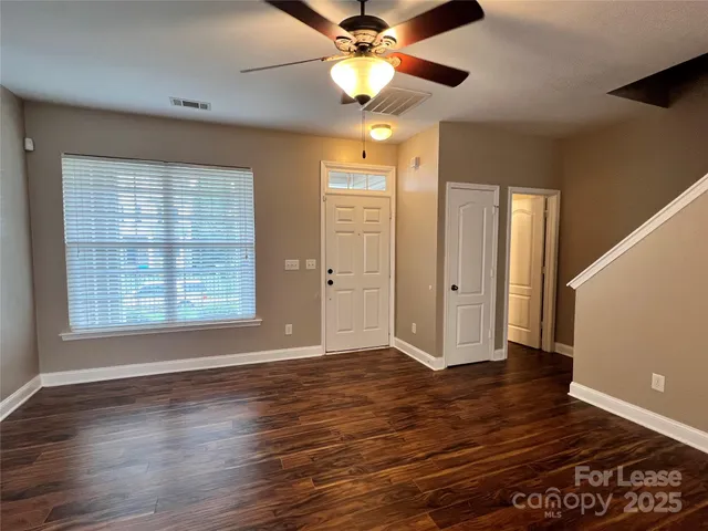 a view of an empty room with window and wooden floor