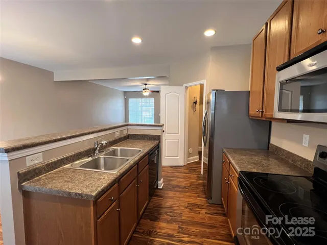 a kitchen with granite countertop kitchen island stainless steel appliances a refrigerator a stove a sink and a refrigerator