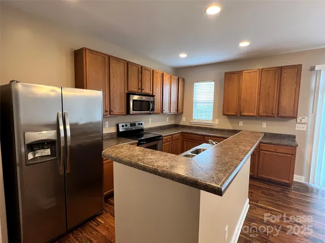 a kitchen with granite countertop a refrigerator stove and sink