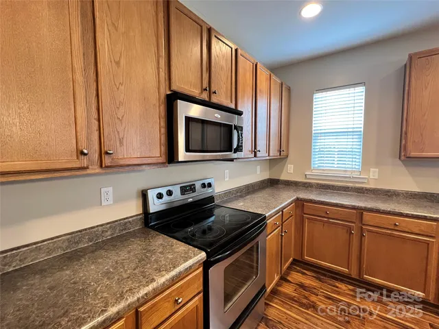 a kitchen with granite countertop a sink stove and microwave