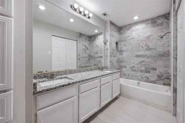 a bathroom with a granite countertop sink a toilet a mirror and shower