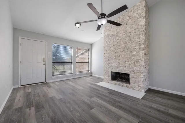 an empty room with wooden floor fireplace and windows
